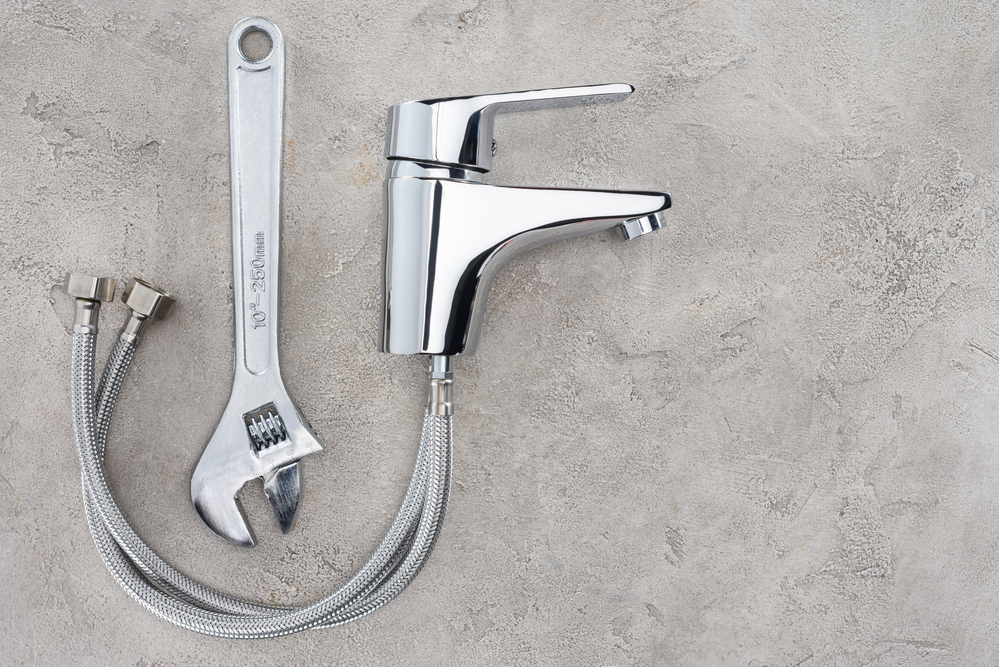 A wrench and a broken faucet in the ground.